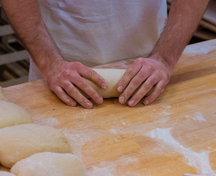 Zręczne ręce piekarza formują podłużne "chlebki"